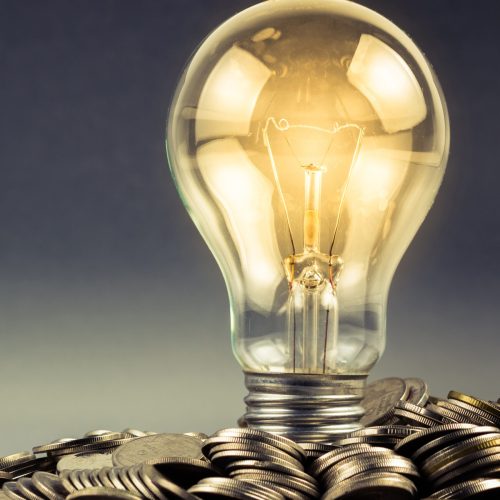 Light bulb and pile of coins with copy space